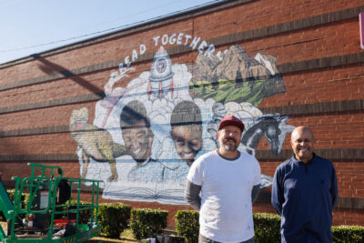 Artist Scott Nurkin poses with Dr. Munro Richardson (left) at a mural Nurkin created to promote reading.